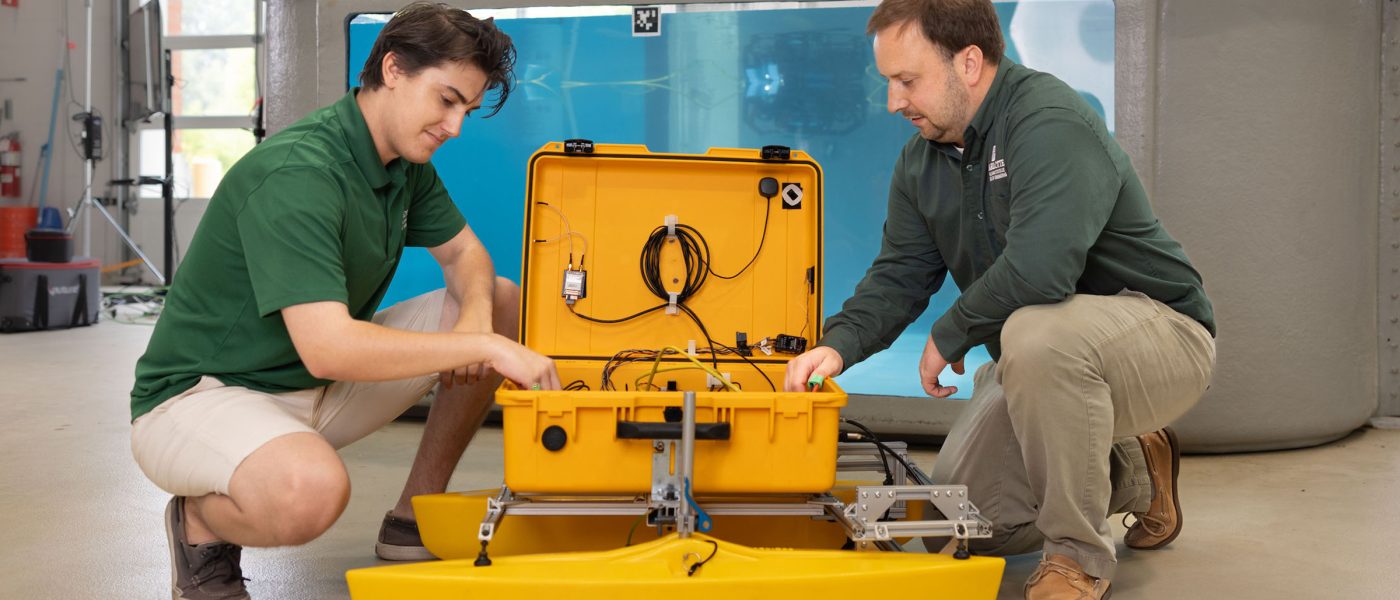 Professor and student working on an autonomous vessel in the BATT CAVE research center